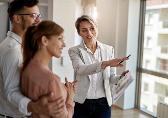 Smiling real estate agent talking with a couple interested in buying a new home.